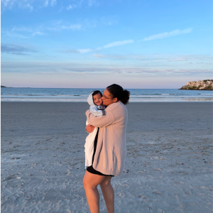 mother holding baby on the beach during the fall season